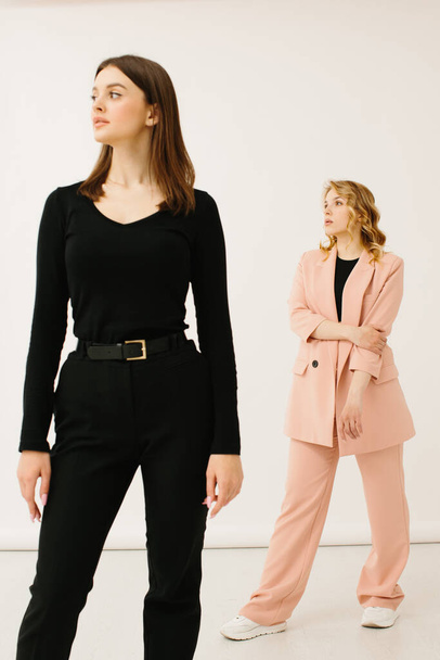 Стильные молодые женщины в пастельных костюмах стоят вместе, концепция моды - фото со склада - Фото, изображение