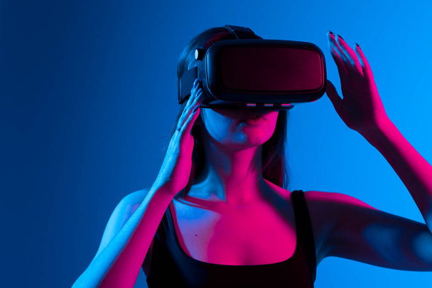 Young woman using VR headset helmet to play simulation game. Watching virtual reality 3d video. Girl in VR goggles looking around. - Foto, Bild