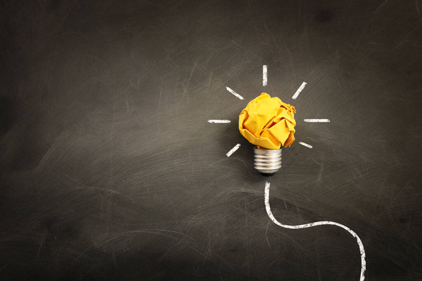 Education concept image. Creative idea and innovation. Crumpled paper as light bulb metaphor over blackboard - 写真・画像