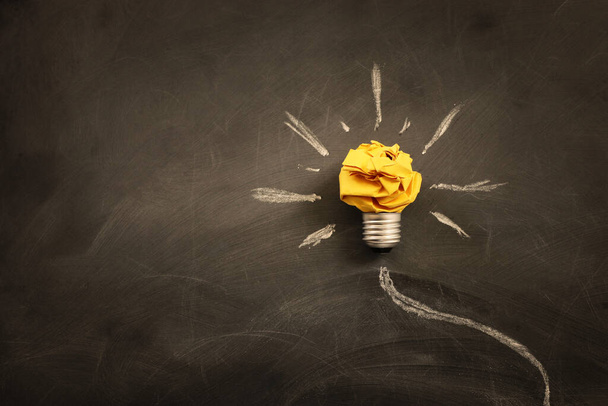 Education concept image. Creative idea and innovation. Crumpled paper as light bulb metaphor over blackboard - Valokuva, kuva