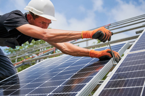 Mannelijke werknemer installeert fotovoltaïsch zonnepaneel buiten. - Foto, afbeelding