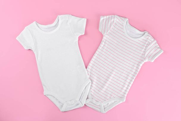 Két fehér pamut baba ruha mockup rózsaszín pasztell háttér. Üres hely szövegnek vagy logónak. Tervezett felépítmény sablon - Fotó, kép