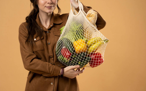 Woman holding mesh grocery bag with vegetables. Concept of no plastic. Zero waste, plastic free. Eco friendly concept. Sustainable lifestyle. - Photo, Image