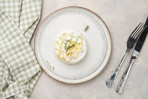 Oven baked camembert cheese on white plate, grey concrete surface. Homemade grilled brie with thyme, scandi style table setting - Fotografie, Obrázek