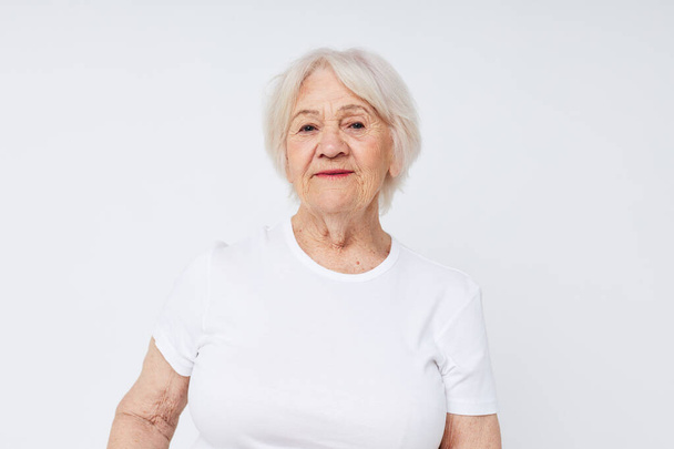 close-up of a cheerful elderly woman in a white t-shirt - 写真・画像