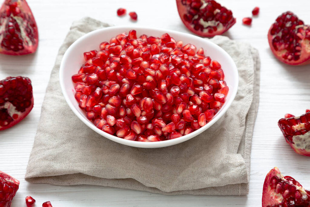 Red Pomegranate Seeds in a White Bowl , low angle view. - 写真・画像