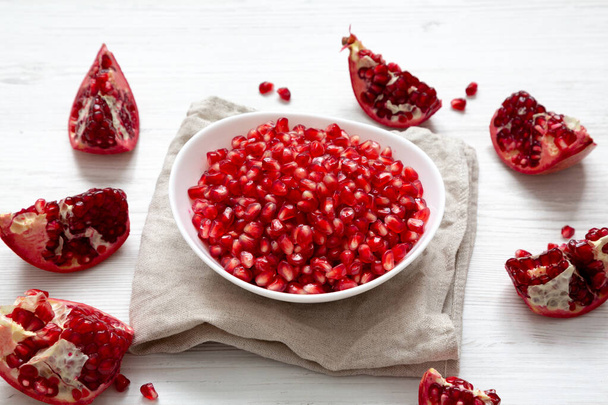 Red Pomegranate Seeds in a White Bowl , side view. - Foto, imagen