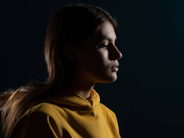 Relaxation and meditation, a young brunette woman, side view, light silhouette on a dark studio background. - Foto, Bild