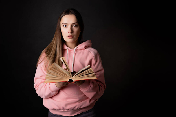 A stunning plot twist in a bestseller, a young brunette reads a book in shock. - Fotografie, Obrázek