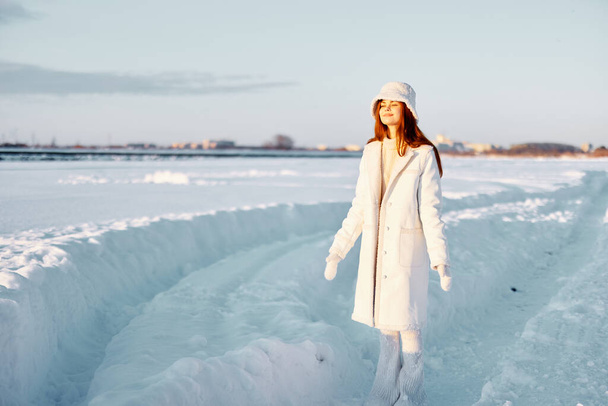 Genç kadın gülümse kış havasında yürü beyaz palto temiz hava - Fotoğraf, Görsel