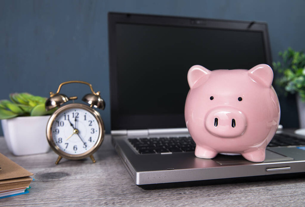 piggy bank on the notebook with clock on working tabl - Foto, immagini