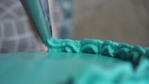 cukierniczka rozsypuje śmietankę łopatką na świeżo upieczonym torcie urodzinowym - Materiał filmowy, wideo