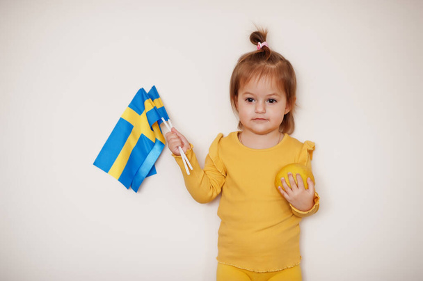 Baby girl in yellow with lemon and Sweden flag, isolated background. - Foto, Imagem
