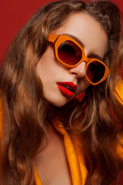 model in de oranje jas en zonnebril - Foto, afbeelding