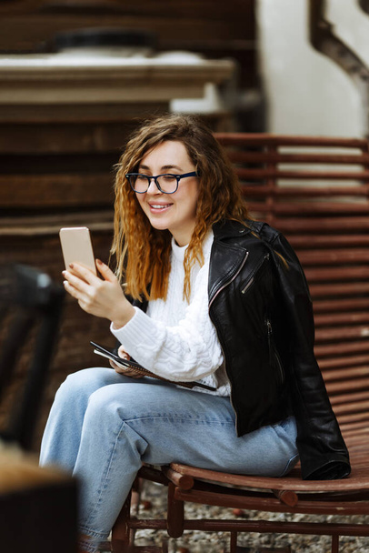 Портрет молодої усміхненої білої жінки, яка використовує мобільний телефон, спілкування, балачки. Щаслива жінка тримає смартфон, купує онлайн або навчається
 - Фото, зображення