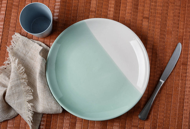 empty plate with knife beside on wooden table - Foto, afbeelding