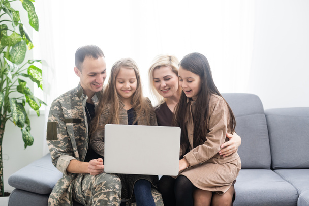 Στρατιωτική πατέρα με την οικογένειά του στον καναπέ στο σπίτι - Φωτογραφία, εικόνα