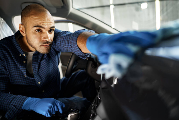 Ένας άνθρωπος που καθαρίζει το εσωτερικό του αυτοκινήτου, αυτοκίνητο λεπτομερώς στην υπηρεσία πλυντηρίου αυτοκινήτων - Φωτογραφία, εικόνα
