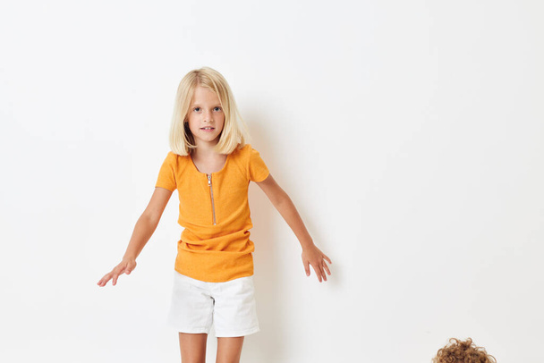 little girl with blond hair in a yellow t-shirt isolated background - Foto, afbeelding