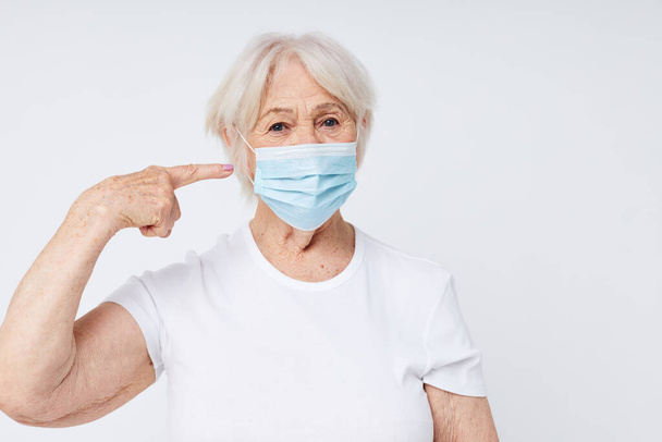 emotional elderly woman respiratory protection light background - Zdjęcie, obraz