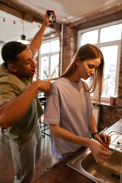 Black guy making video while cutting hair of woman - Фото, зображення