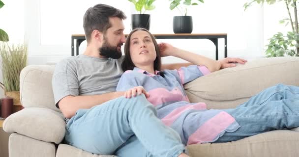 Couple talking on sofa at home - Materiał filmowy, wideo