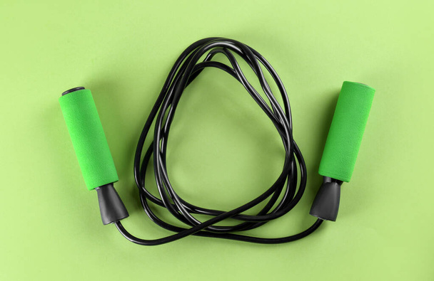 Skipping rope on light green background, top view. Sports equipment - Fotó, kép