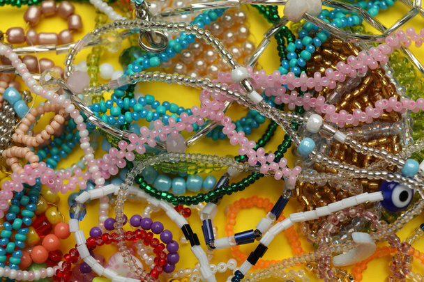 Pile of beautiful handmade beaded jewelry on yellow background, closeup - Photo, Image