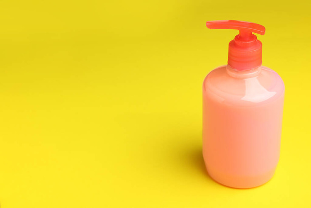 Bottle of liquid soap on yellow background, space for text - Foto, Imagen
