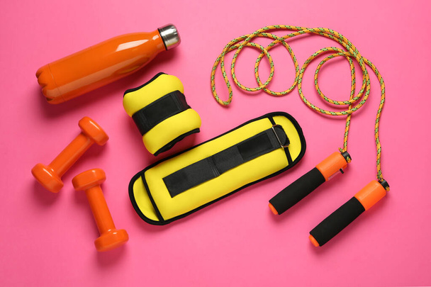 Yellow weighting agents and sport equipment on pink background, flat lay - Photo, image