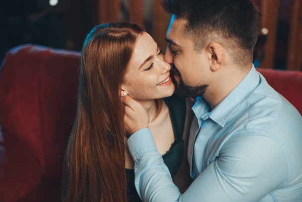 Close-up portrait of happy caucasian couple kissing and enjoying a good time together on valentine day on sofa. Couple celebrating Valentines Day, Womens Day - Photo, Image