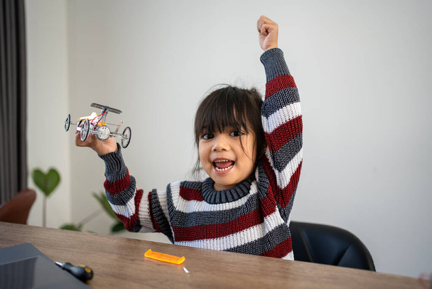 Asian girls enjoy making and fixing electrical robot car and learning online tutor training course and Raise your hand for happiness and success - Zdjęcie, obraz
