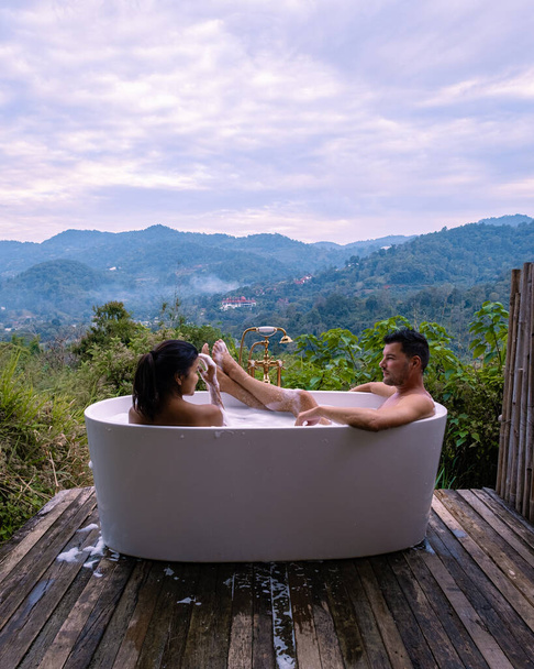 Bath tub during sunset in the mountains of Chiang Mai Thailand, elaxing in outdoor wood fire hot tub out in the wilderness - Photo, Image