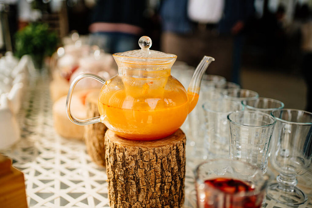 kettle with hot fruit tea on a log stand.  - 写真・画像