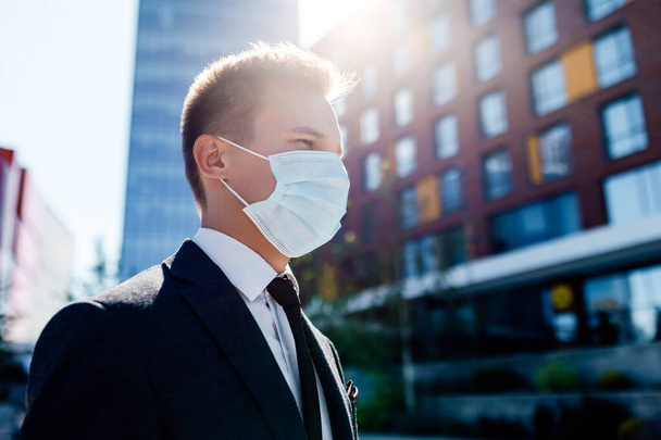 Businessman and coronavirus epidemic. Close up portrait of young business man in a disposable facial mask - Foto, Imagen