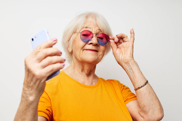 Photo of retired old lady in fashionable glasses with a smartphone in hand cropped view - Фото, зображення