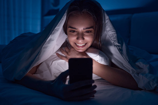 Happy woman watching video on cellphone at night - Photo, Image