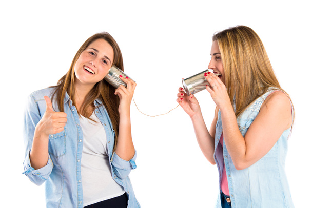 Freunde sprechen durch ein Blechtelefon auf weißem Hintergrund - Foto, Bild