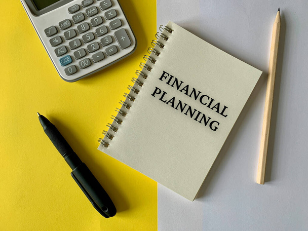 Testo di pianificazione finanziaria su blocco note con sfondo calcolatore, penna e matita. Concetto aziendale. - Foto, immagini