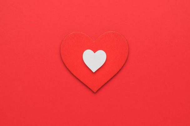 A big red and a small white heart on a red background. The concept of falling in love and Valentine's day. Minimalism. Flat lay. - Foto, imagen