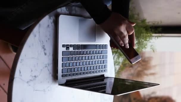Una donna si siede in un caffè e lavora in un computer portatile. - Filmati, video