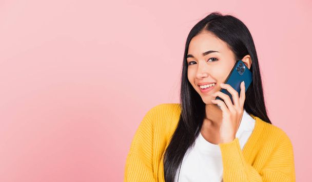Portrait Asian happy beautiful young woman smile talking by smartphone looking to camera isolated, studio shot isolated on pink background, Thai female hold the phone to calling with copy space - Фото, зображення