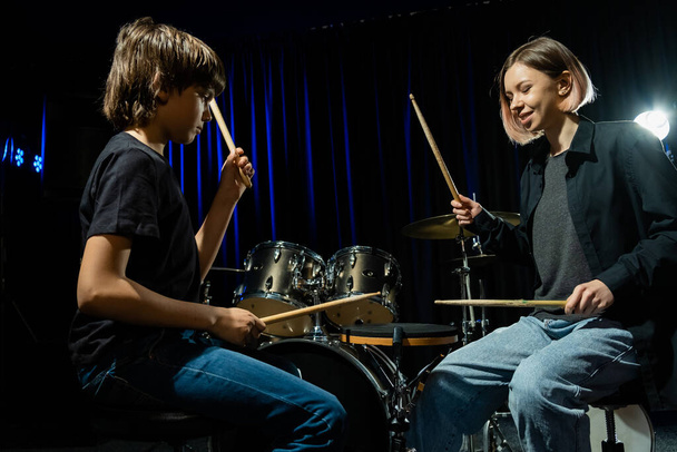 Young woman teaching boy to play drums. - Foto, immagini
