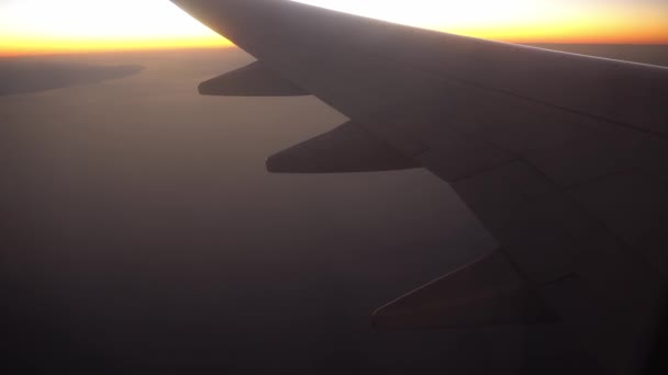 Αεροπλάνο πετά πάνω από τη θάλασσα και την έρημο στο ηλιοβασίλεμα ή την ανατολή του ηλίου, η θέα από το παράθυρο στην πτέρυγα του αεροπλάνου και πτερύγια. - Πλάνα, βίντεο