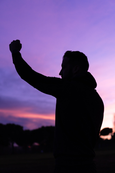 Siluetti urheilija nostaa nyrkki ylös auringonlaskun aikaan - Valokuva, kuva