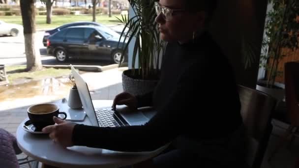 Žena sedí v kavárně a pracuje v laptopu. - Záběry, video