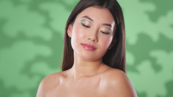 Přírodní krása a organická kosmetika. Mladá asijská dáma bez košile pózuje s monstera list, hladí její tělo - Záběry, video