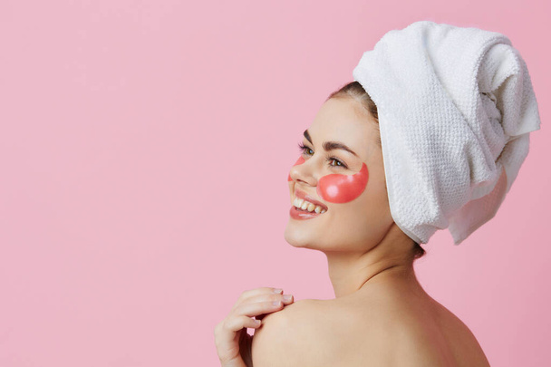 piękna kobieta różowe plamy na twarzy z ręcznikiem na głowie różowy tło - Zdjęcie, obraz