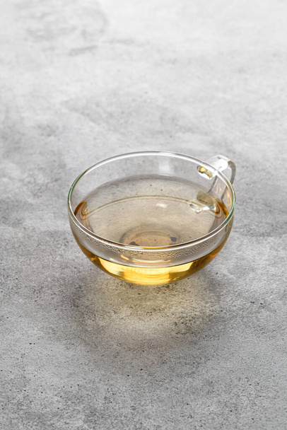 A glass with green herbal tea on grey background. Minimalism. Cup of tea. Mug - Zdjęcie, obraz