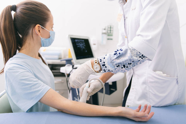 Lekarz robi USG ręki z zamkniętymi rękami. Lekarz pokazuje pacjentowi wyniki USG. USG medyczne. Rehabilitacyjne zastosowanie botoksu do rozluźnienia mięśni - Zdjęcie, obraz